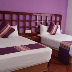 - 2 lits dans une chambre aux murs violets dans l'établissement Hotel D Abril, à Santa Cruz Huatulco