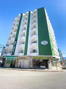 阿帕雷西達的住宿－MAPP Hotel Aparecida-SP，一座绿色的白色建筑,前面有一位妇女