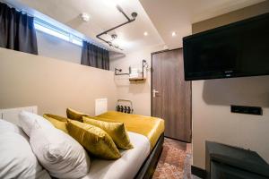 a bedroom with a bed with gold pillows and a flat screen tv at The Alfred Hotel in Amsterdam