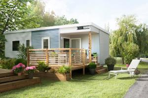 a tiny house with a deck and a chair at Camping Le Walric in Saint-Valéry-sur-Somme