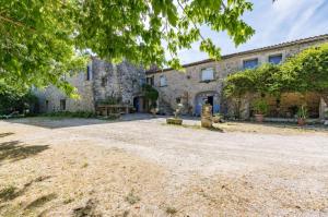 una vista exterior de una casa de piedra con patio en Auberge de Saugras, en Argelliers