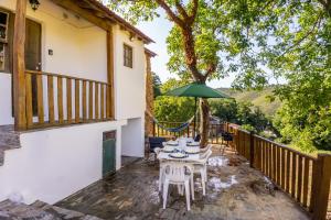 a patio with a table and chairs and an umbrella at Casa da Corriça - Alojamento Local in Negreda
