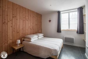 a small bedroom with a bed and a window at Gîte de Granit GRIS in Besse-et-Saint-Anastaise