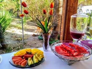 a table with two plates of fruit and a glass bowl of vegetables at Pousada Rancho dos Ipês in Alto Paraíso de Goiás