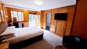una camera d'albergo con letto e TV di Farnham House Hotel a Farnham