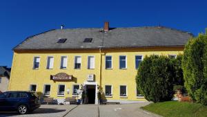 a yellow building with a car parked in front of it at Pension & Gasthof Erbgericht Höhenlage 850m in Marienberg