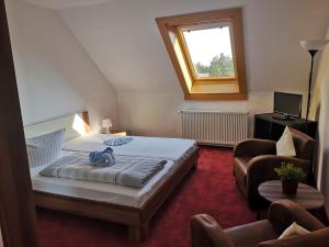 a bedroom with a bed and a window and a chair at Pension & Gasthof Erbgericht Höhenlage 850m in Marienberg