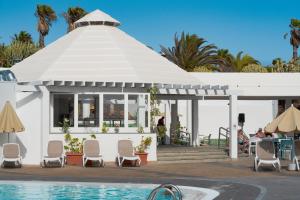 a white pavilion with chairs and a pool at Relaxia Lanzasur Club - Aqualava Water Park in Playa Blanca