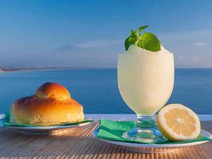 a drink in a glass next to a plate of food at Villaggio Albergo Internazionale La Plaja in Catania