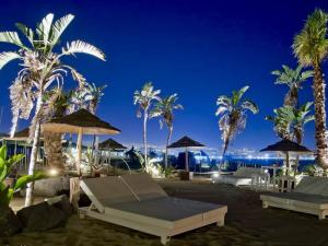 een resort met palmbomen en parasols en de oceaan bij Villaggio Albergo Internazionale La Plaja in Catania