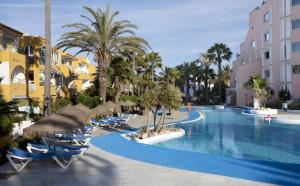 a pool at a resort with chairs and palm trees at Playalinda in Roquetas de Mar