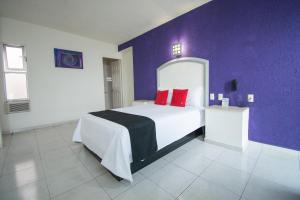 a bedroom with a large bed with a purple wall at Hotel Rivoli in León