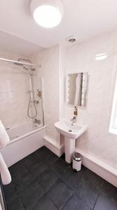 y baño blanco con lavabo y ducha. en Farnham House Hotel en Farnham