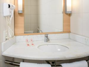 ein Bad mit einem Waschbecken und einem Spiegel in der Unterkunft ibis Belem Aeroporto in Belém