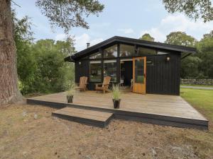 a black tiny house with a wooden deck at Blue Pine Lodge in Dornoch