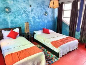 two beds in a room with a blue wall at Riad Beldy in Essaouira