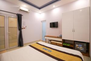 een slaapkamer met een bed en een tv aan de muur bij Hotel Hương Đào in Con Dao
