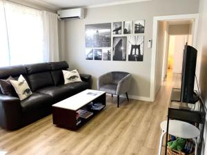 sala de estar con sofá negro y mesa en Top Mosman Location en Sídney