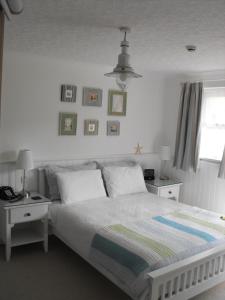 a bedroom with a white bed with two tables and two lamps at Beachlands Hotel in Weston-super-Mare