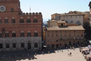 un gruppo di persone che camminano per una città con edifici di I Balconcini a Siena