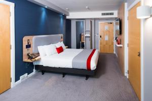 a bedroom with a bed and a blue wall at Holiday Inn Express Leeds City Centre - Armouries, an IHG Hotel in Leeds