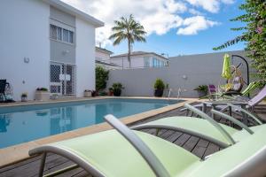 a swimming pool with lounge chairs next to a building at Snooker House in Ponta Delgada