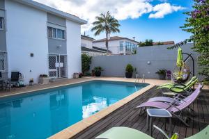 a swimming pool with chairs and a house at Snooker House in Ponta Delgada