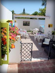 un patio con mesas blancas, sillas y flores en Magnolia, en Alezio