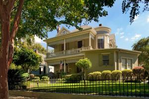 a yellow house with a fence in front of it at Devereaux Shields House in Natchez