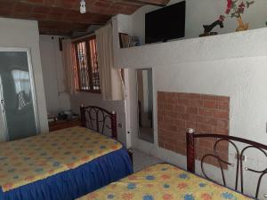 a bedroom with two beds and a tv on the wall at Casa Bertha in Guanajuato