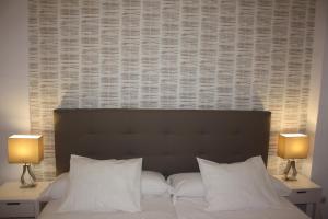 1 dormitorio con 1 cama con almohadas blancas y 2 lámparas en Coliseo Premium Apartment, en Sevilla