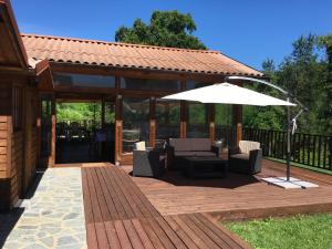 une terrasse en bois avec un parasol et des chaises dans l'établissement Cascina Gardina, à Castellero