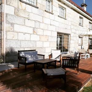 d'une terrasse avec une table, des chaises et un mur en briques. dans l'établissement Os Areeiros Turismo Rural & Bodega, à Santa Cristina de Cobres