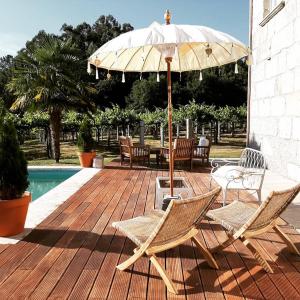 un patio con mesa, sillas y sombrilla en Os Areeiros Turismo Rural & Bodega en Santa Cristina de Cobres