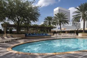 une piscine avec des chaises et des palmiers ainsi qu'un bâtiment dans l'établissement Four Seasons Hotel Houston, à Houston