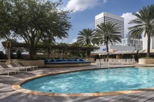 a swimming pool with chairs and palm trees and a building at Four Seasons Hotel Houston in Houston