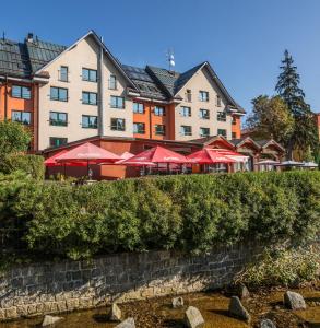 a hotel with red umbrellas in front of a building at Pension Böhmerwald in Železná Ruda