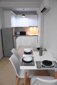 a kitchen with a table and white chairs and a kitchen with a refrigerator at Click Apartments - Tirana in Tirana