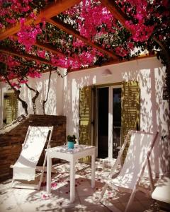 two chairs and a table on a patio with pink flowers at Aegeo Inn in Antiparos