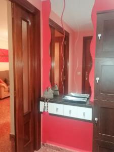 Cette chambre est dotée d'un mur rouge et d'un miroir. dans l'établissement APARTAMENTO Casa Corazones de Teruel, à Teruel