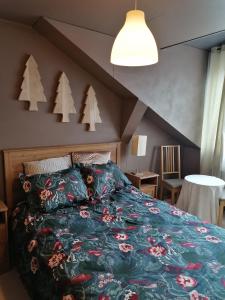 a bedroom with a bed with a green comforter and trees on it at Le gîte du Palayau in Bastogne
