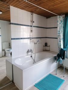 een badkamer met een wit bad en een toilet bij Le gîte du Palayau in Bastenaken