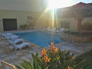 a swimming pool with white chairs and a fountain at Hotel Minas Palace in Passos