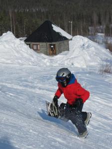 a man riding a snowboard down a snow covered slope at B&B uniikki majoitus maalaisidyllissä in Tervola +37 photos