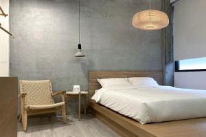 - une chambre avec un lit, une chaise et deux lumières dans l'établissement Little Inn by LAGOM, à Kaohsiung