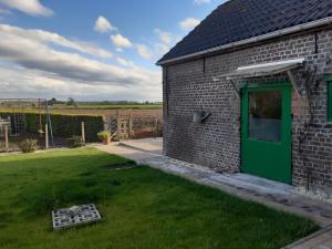 een bakstenen gebouw met een groene deur in een tuin bij Vakantiewoning Zonnehof in Sint-Margriete