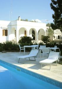 une piscine avec des chaises et une maison en arrière-plan dans l'établissement Villa Curri, à Locorotondo