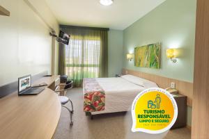 una camera d'albergo con letto e scrivania con un cartello di Eko Residence Hotel - a 200m dos Hospitais da Santa Casa a Porto Alegre