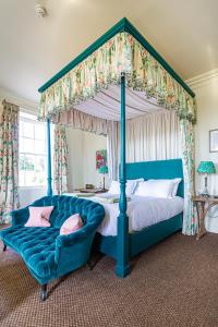 uma cama de dossel azul com um sofá azul num quarto em The Talbot, Malton, North Yorkshire em Malton
