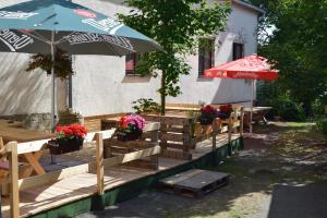 a wooden deck with tables and an umbrella and flowers at Hotel Carola in Schönheide